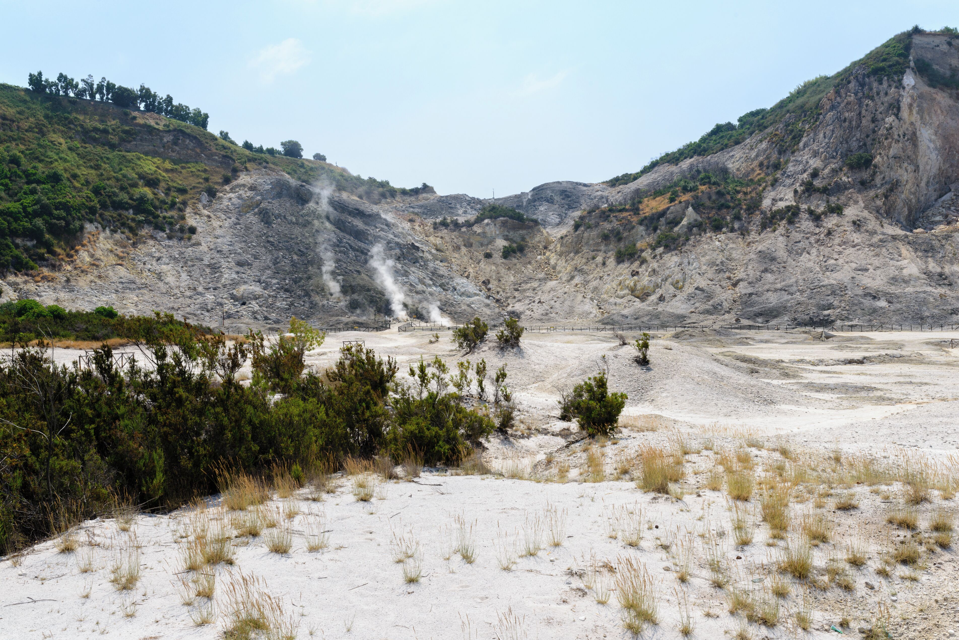 A dry, rocky landscape with sparse vegetation and a small stream.