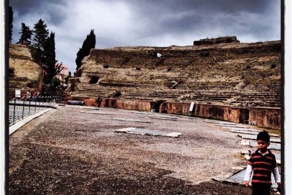 Un sitio histórico con ruinas, un niño y un cielo nublado.