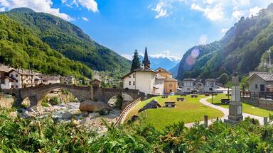 Lillianes, Aosta Valley. Italy. View of the stone bridge over the Lys stream, the Church of San Rocco and the cemetery. July 27, 2022.