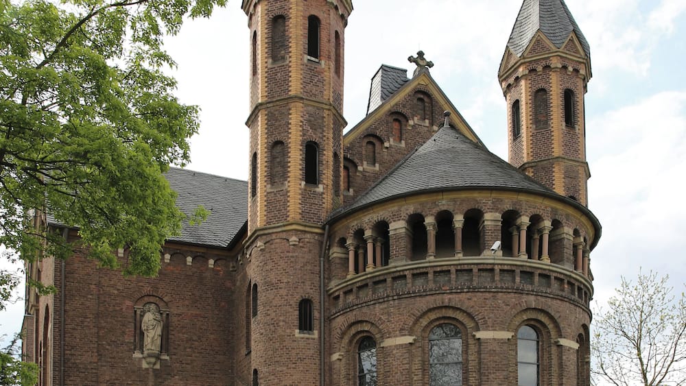 A historic church with two prominent towers and a central round tower.