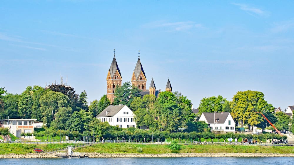 Ein Fluss mit einer Burg und mehreren Häusern im Hintergrund.