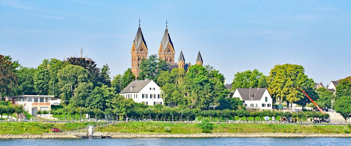 A river with a castle and several houses in the background.