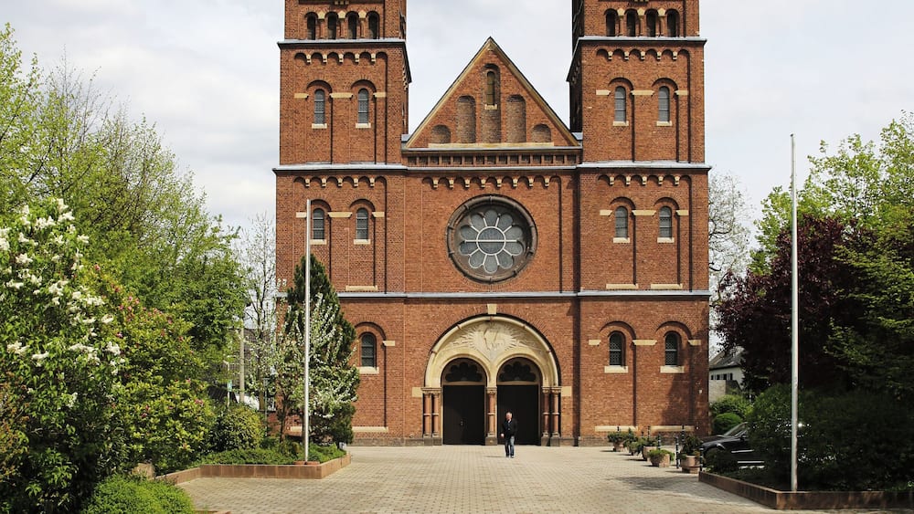A large brick church with two towers and a central clock.
