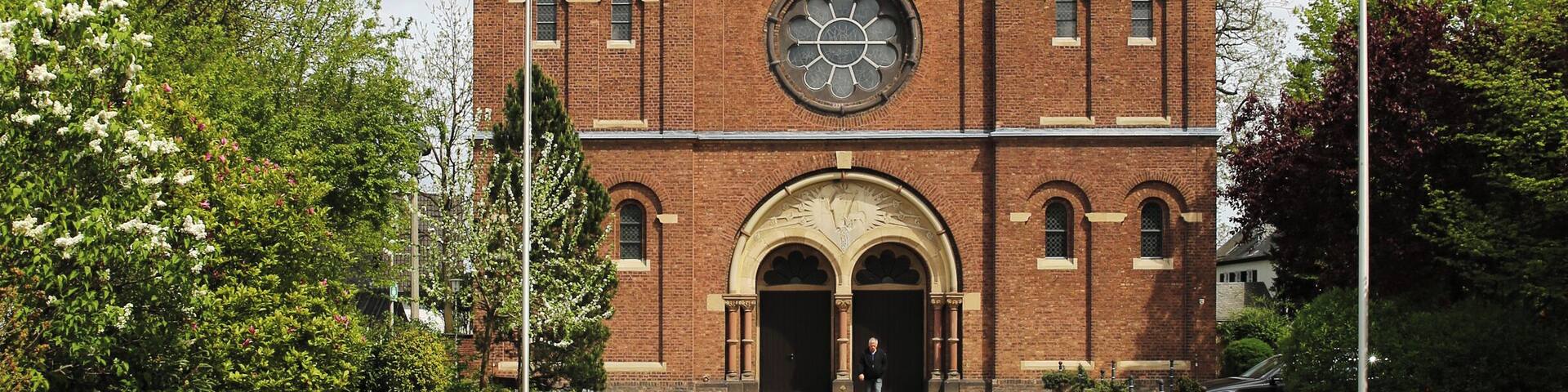 A large brick church with two towers and a central clock.