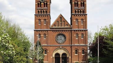 Uma igreja de tijolos com duas torres e um relógio central.