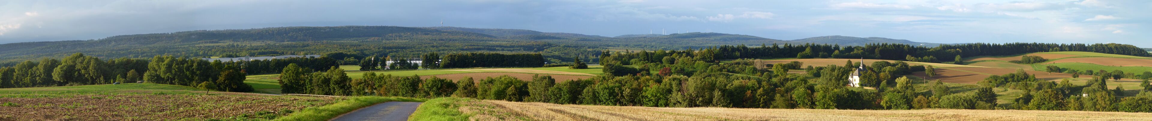 A rural landscape with rolling hills, fields, and a church.