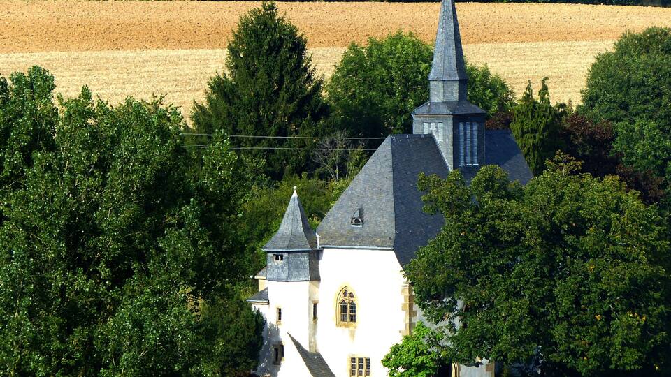 A church with a steeple surrounded by trees and fields.