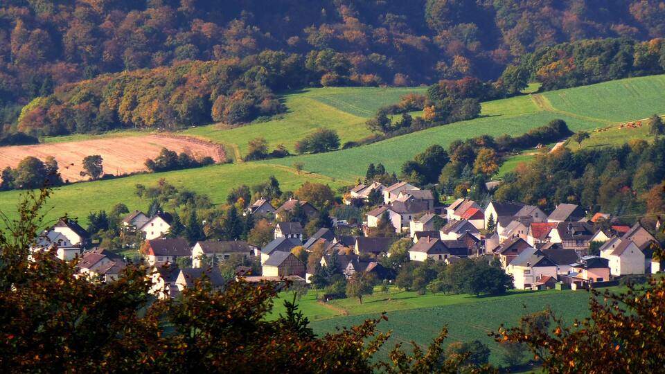 A rural village nestled in rolling hills with houses clustered together.