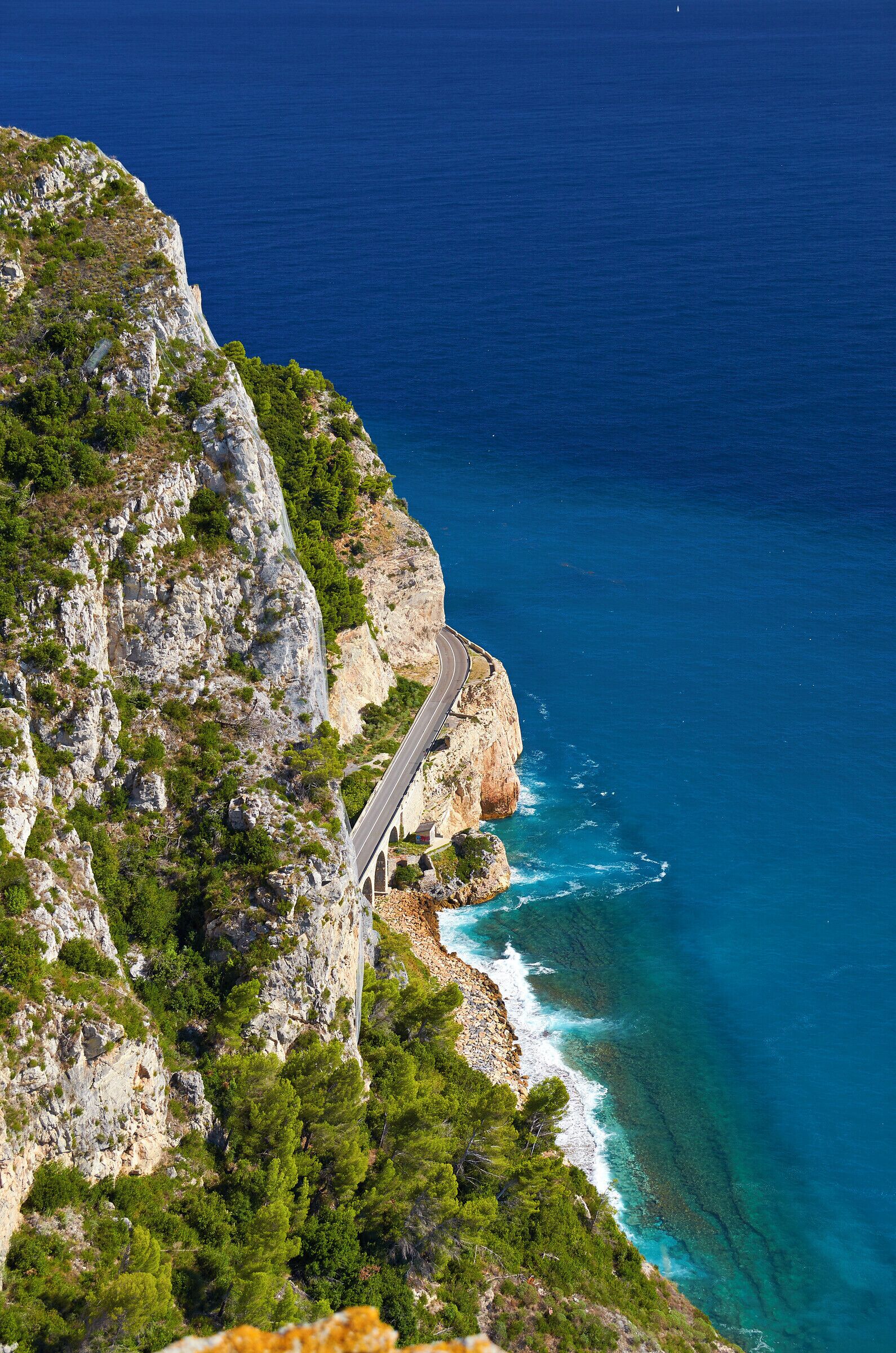 A coastal road winding along a cliffside with the ocean in the background.