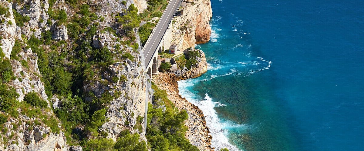 Une route côtière sinueuse qui longe une falaise, avec l’océan en toile de fond.