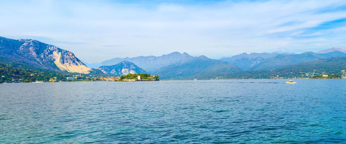 A lake with mountains in the background and a small island with buildings.