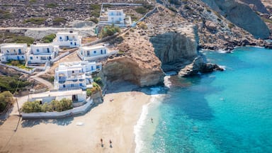 Uma vila costeira com edifícios brancos, uma praia de areia e águas azul-claras.