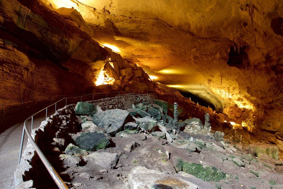 Een grot met stalactieten en -stalagmieten, een pad en een leuning.