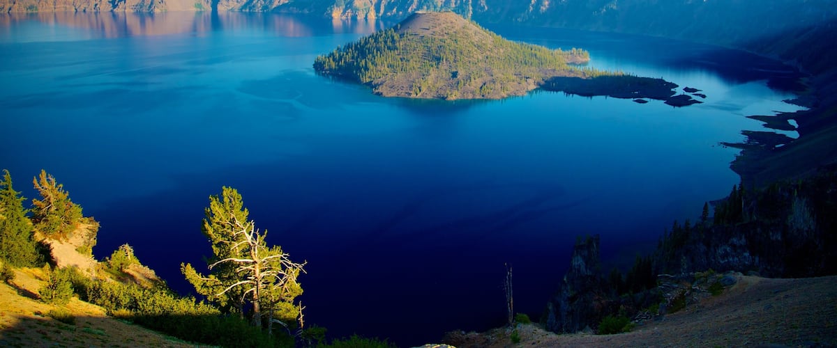 Un lago extenso rodeado de montañas y bosques frondosos.