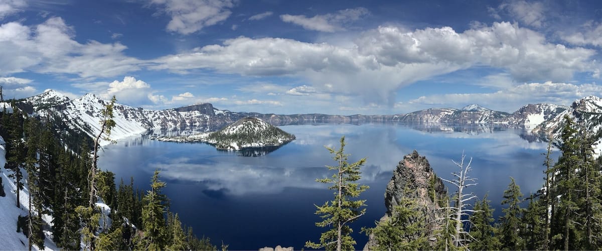 A serene lake surrounded by snow-capped mountains and dense forests.