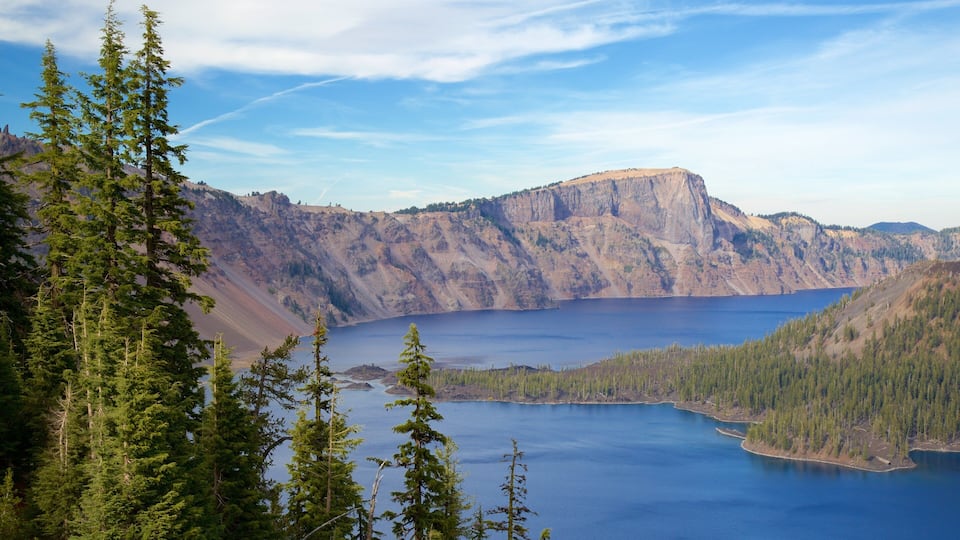 A mountainous landscape with a large lake surrounded by dense forests and rugged cliffs.