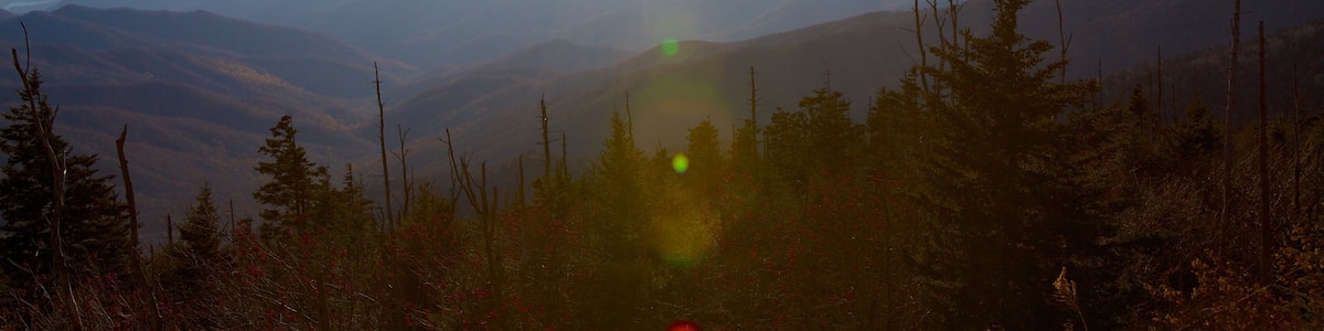 A mountain landscape with a clear sky and the sun shining.