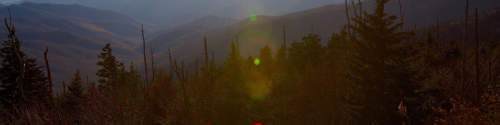 A mountain landscape with a clear sky and the sun shining.