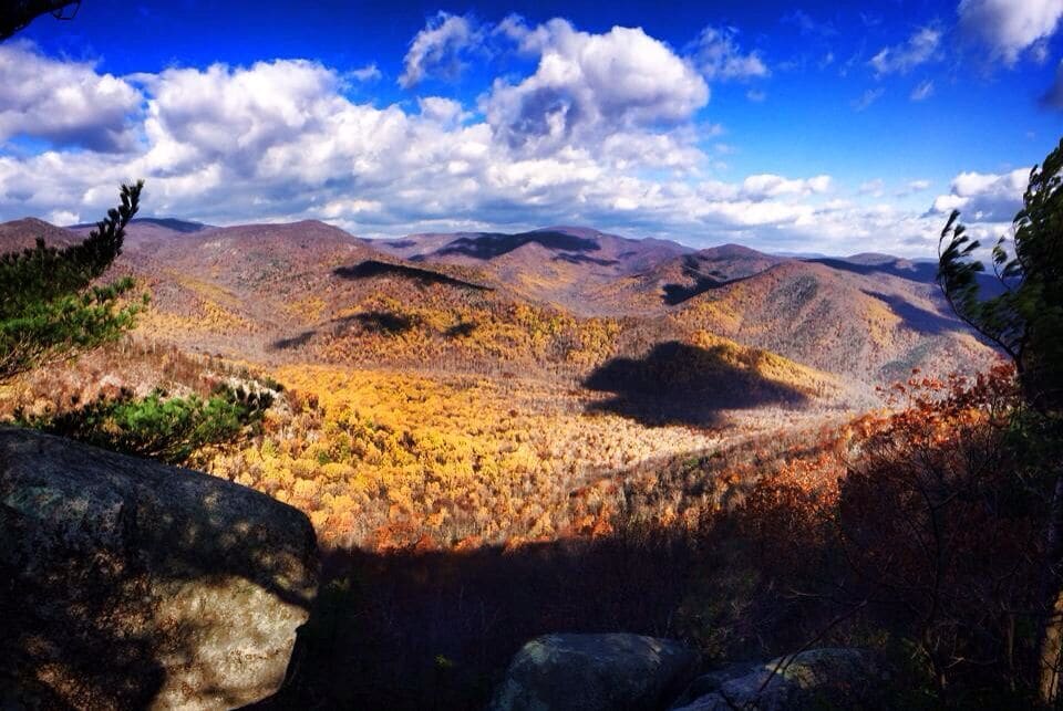 Un paysage montagneux aux couleurs automnales, avec un terrain rocheux et un ciel bleu dégagé.