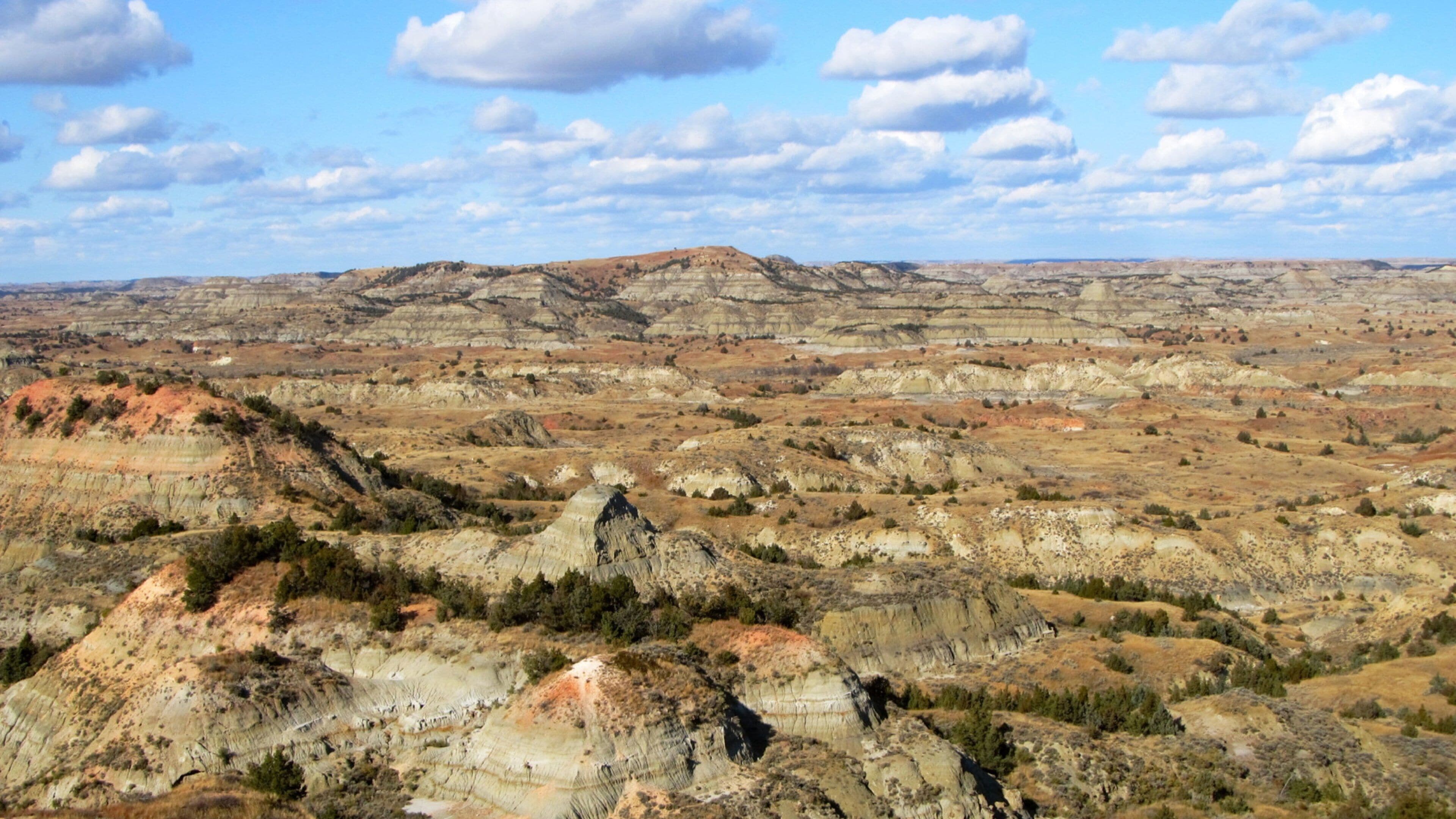 A vast landscape of rugged terrain with layered rock formations and sparse vegetation.