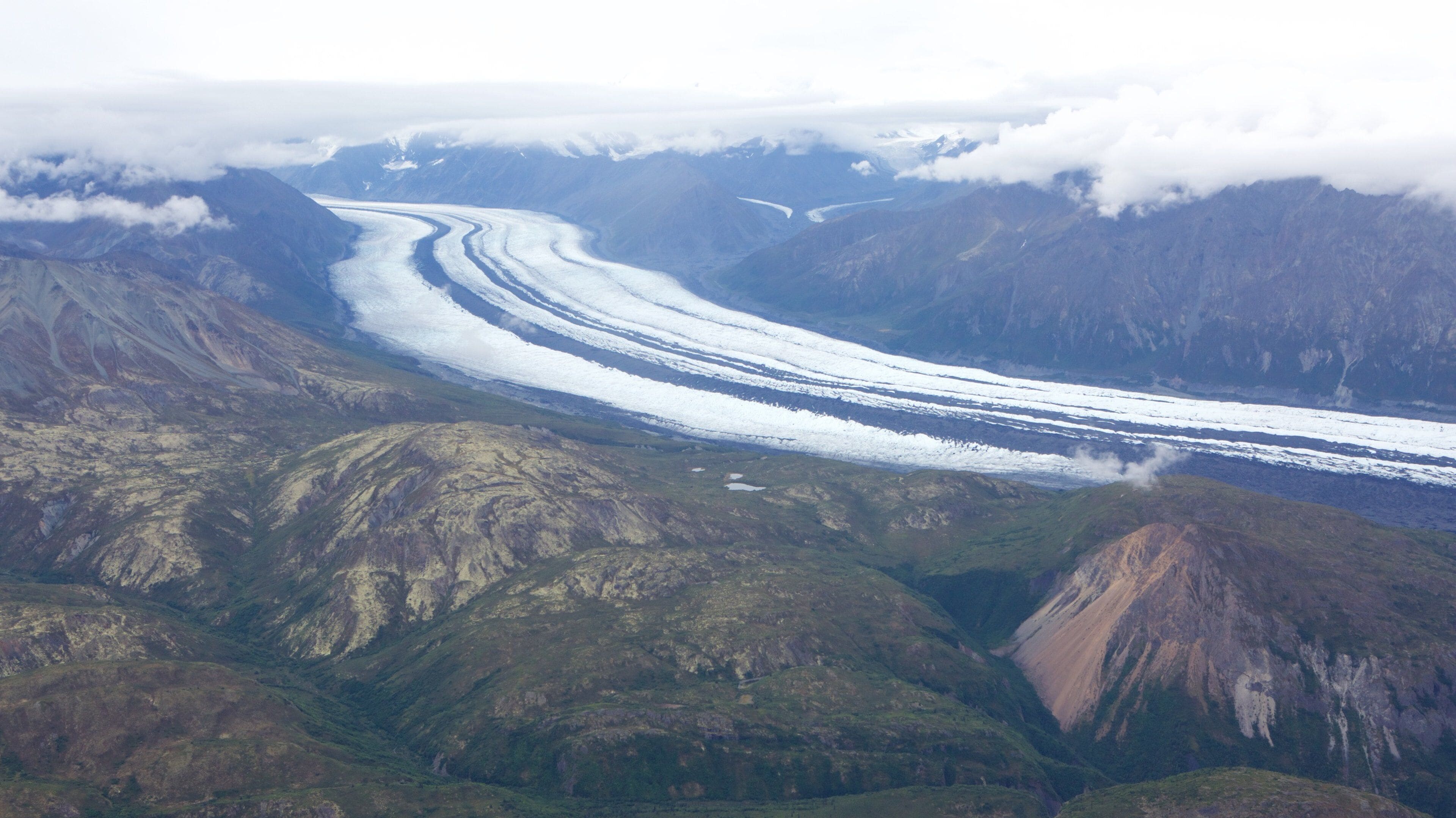 A glacier winding through a mountainous landscape.