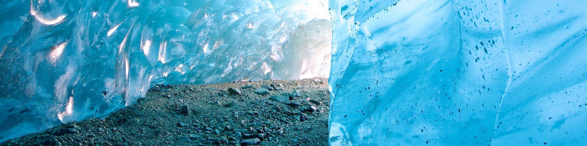 An ice cave with a rocky floor and blue ice formations.