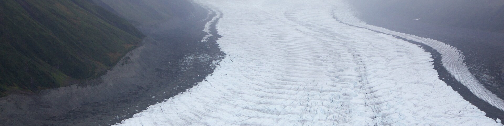 Um glaciar com uma fenda no centro, rodeado por montanhas.