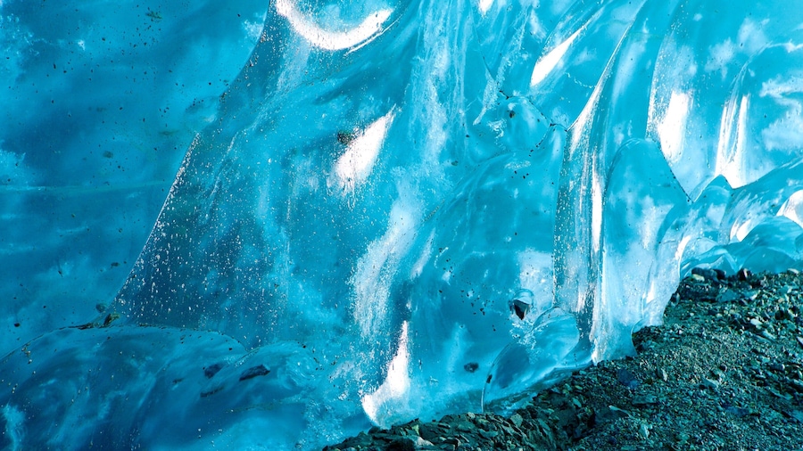 A close-up of a glacial ice formation with visible cracks and a rocky base.