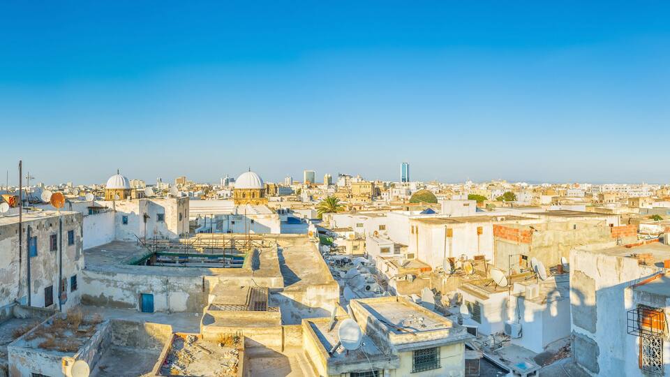A cityscape with a prominent minaret and domed buildings under a clear blue sky.