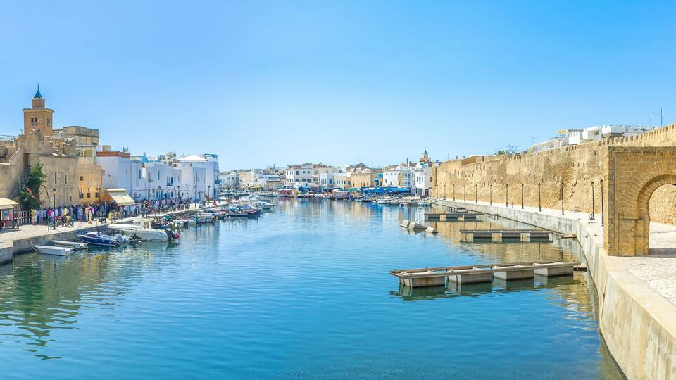 A canal with boats, a stone wall, and historic buildings.