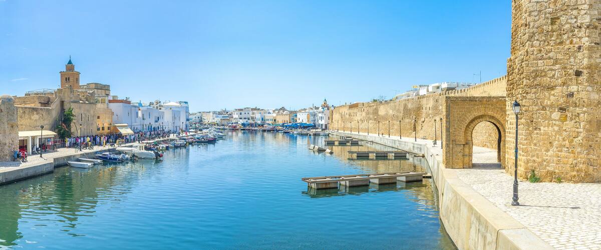A canal with boats, a stone wall, and historic buildings.