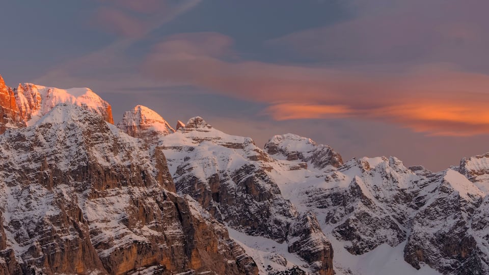 Snow-covered mountains with a sunset sky.
