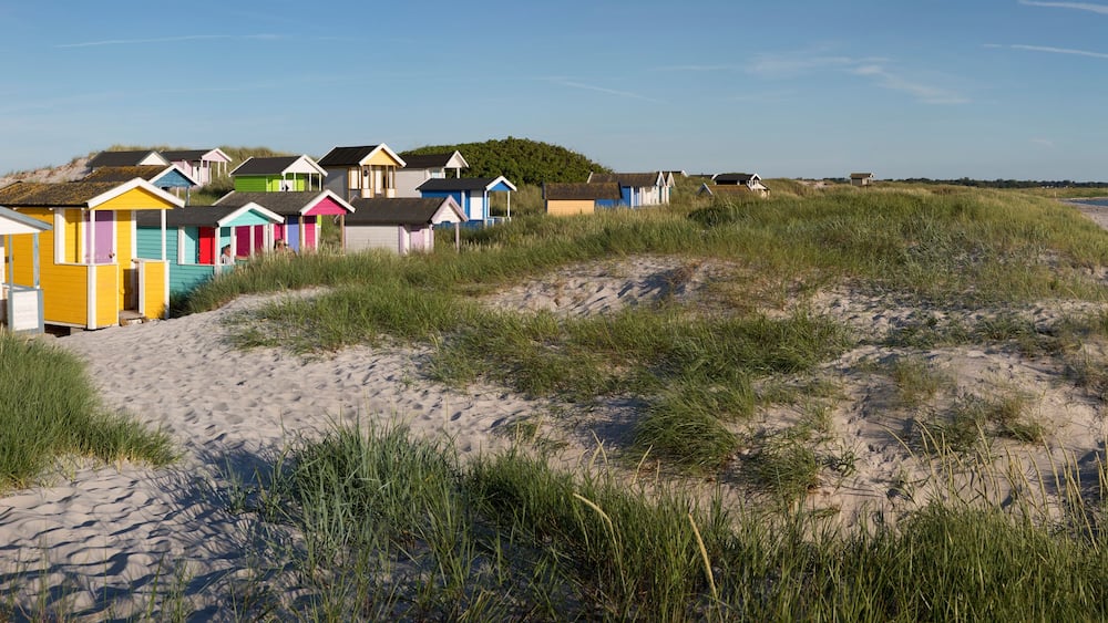 A beach with colorful beach huts and a sandy shoreline.