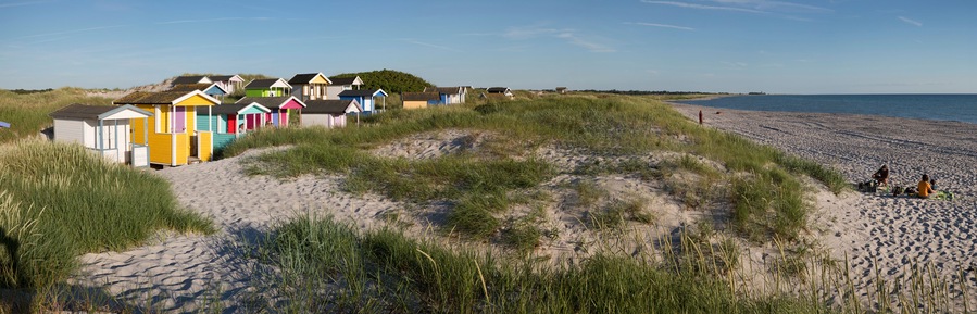 Una playa con cabañas de colores y una orilla arenosa.
