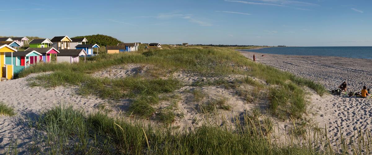 A beach with colorful beach huts and a sandy shoreline.