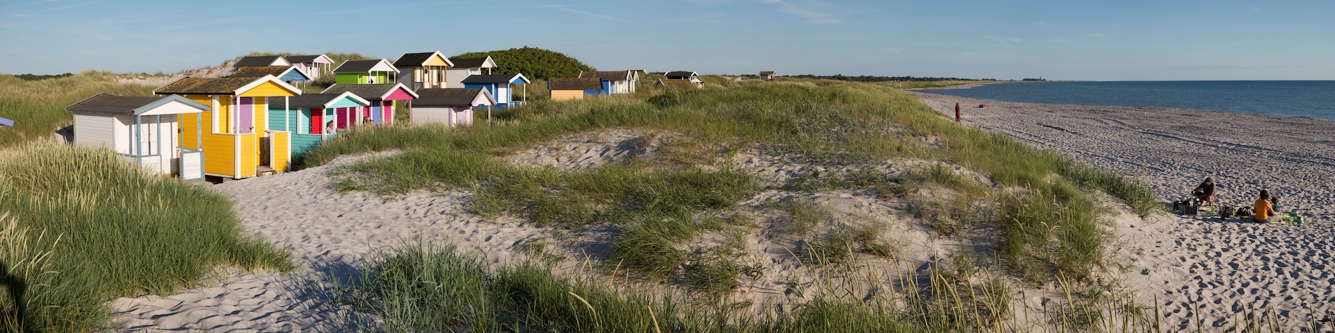 A beach with colorful beach huts and a sandy shoreline.