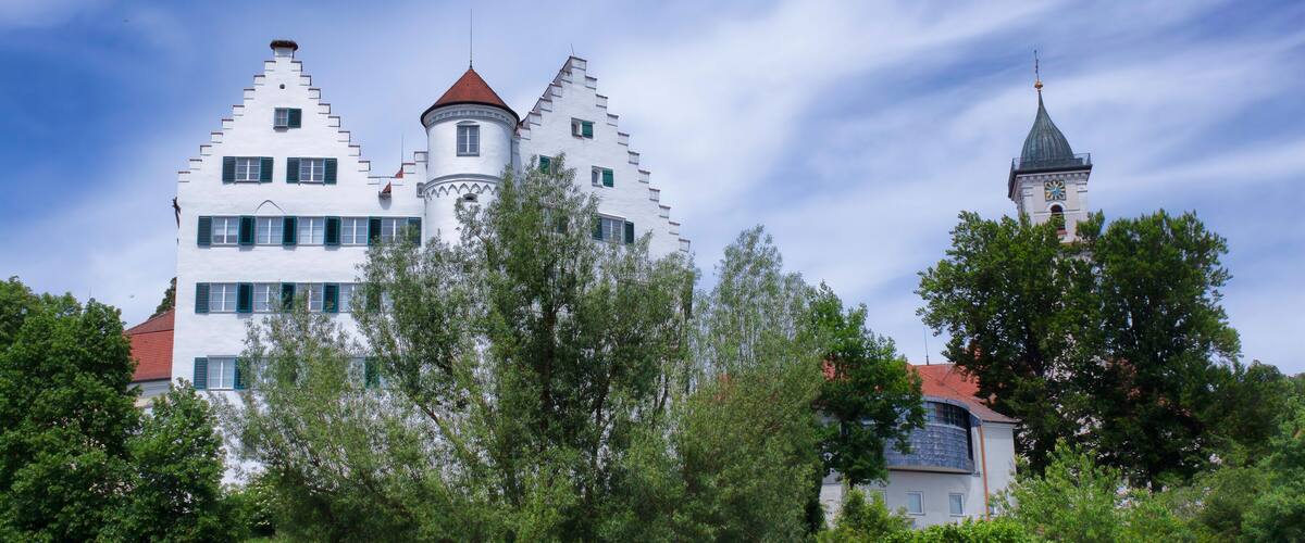 A white castle with a red roof and a tower with a clock.