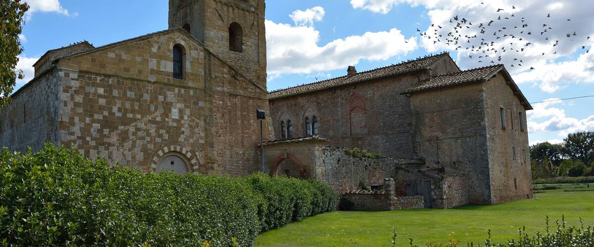 A historic stone church with a bell tower and a courtyard.