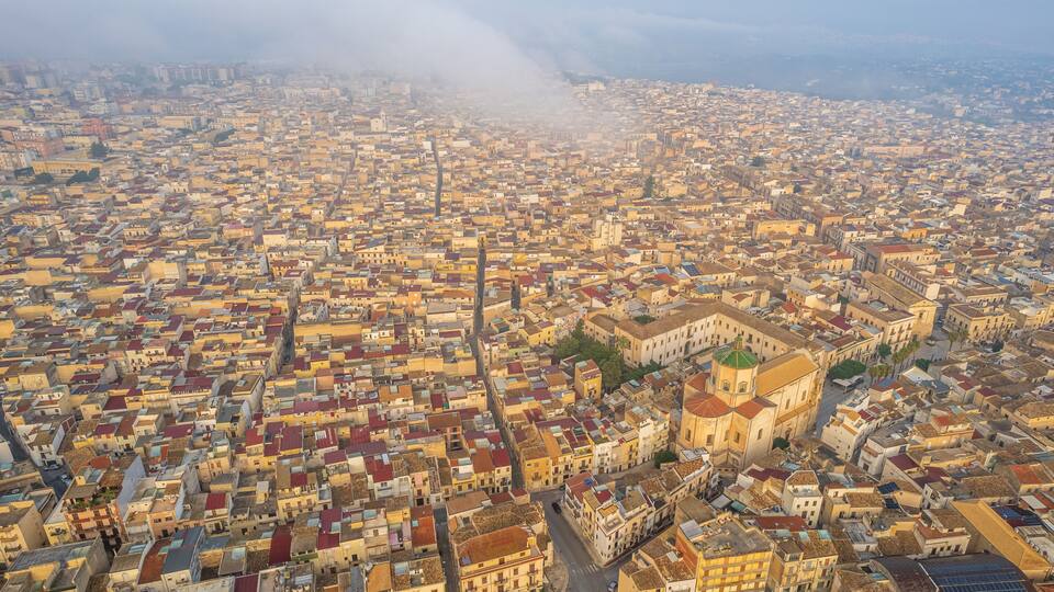 A densely packed urban area with a prominent historical building featuring a green dome.