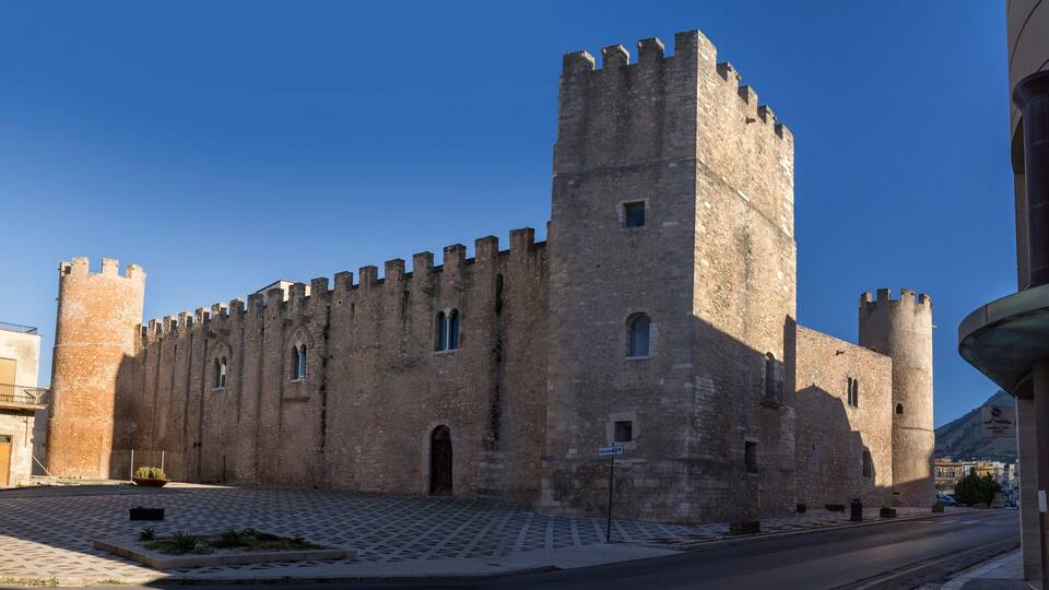 A historic stone castle with battlements and a tall central tower.