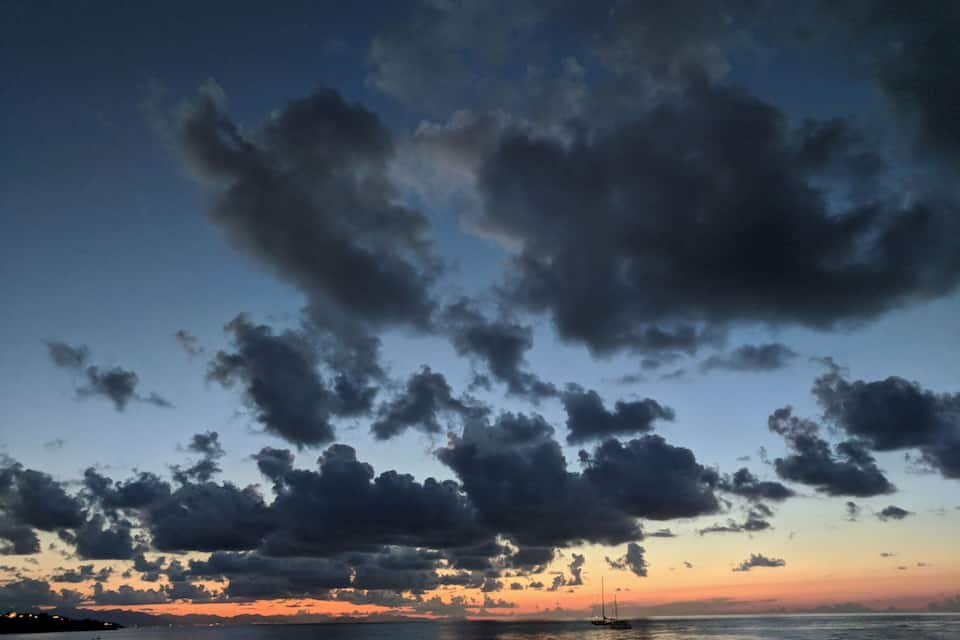 A sunset over a body of water with scattered clouds.