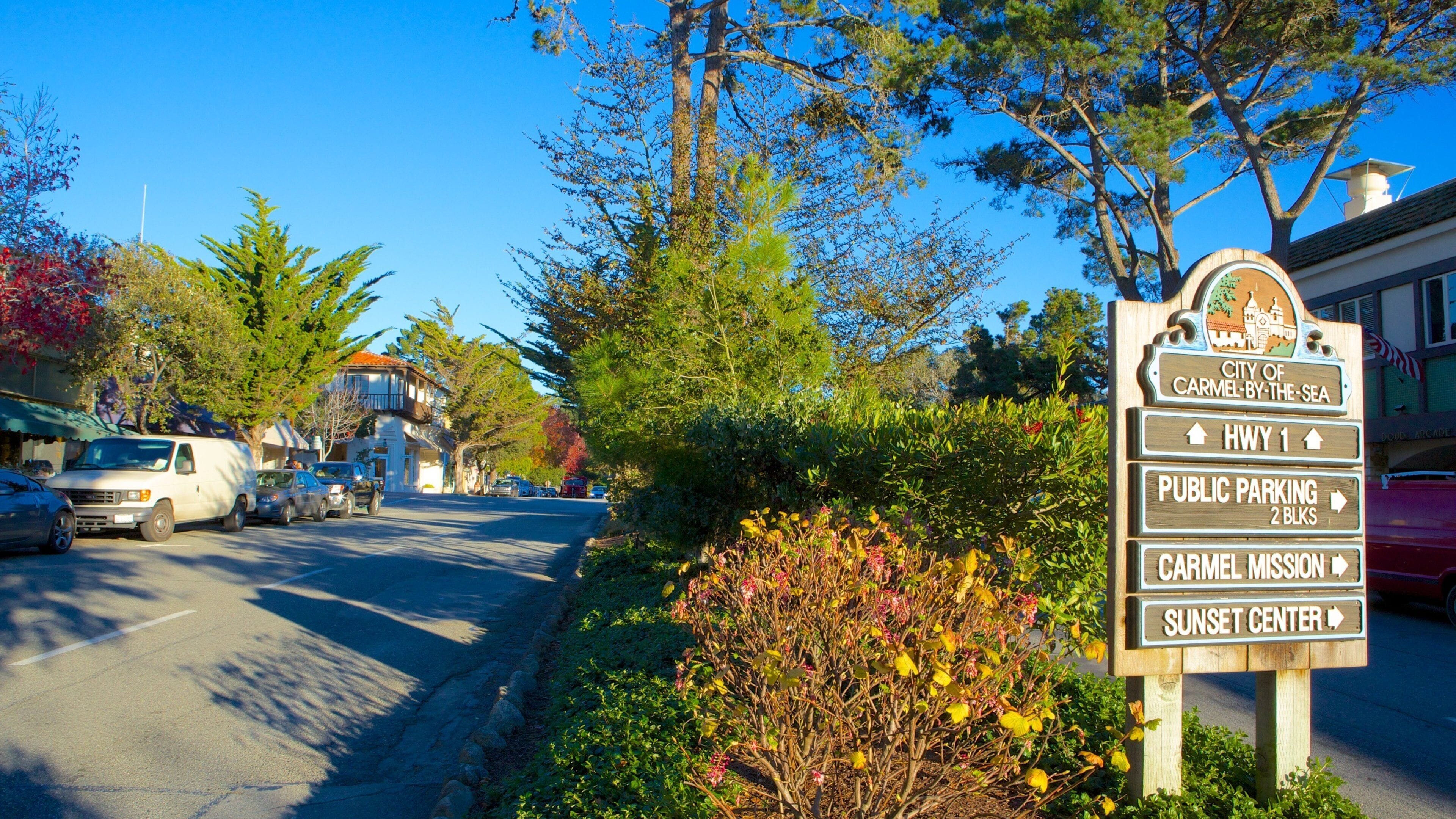 A street sign with directions to City of Carmel-by-the-Sea, HWY 1, Public Parking 2 Blks, Carmel Mission, and Sunset Center.