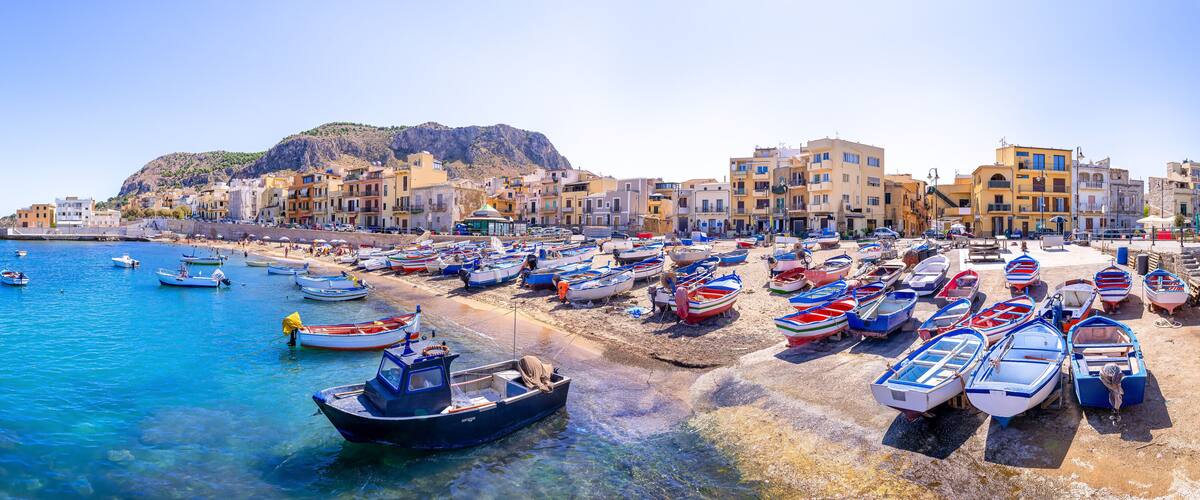 A coastal town with colorful buildings, a beach, and numerous small boats.