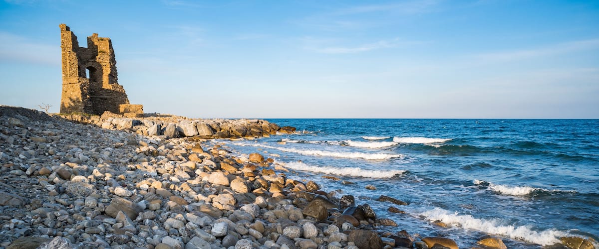A rocky shoreline with a historic stone structure.