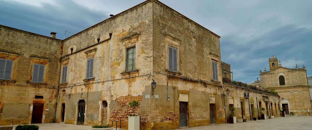 A historic building with a stone facade, multiple windows, and a bell tower.