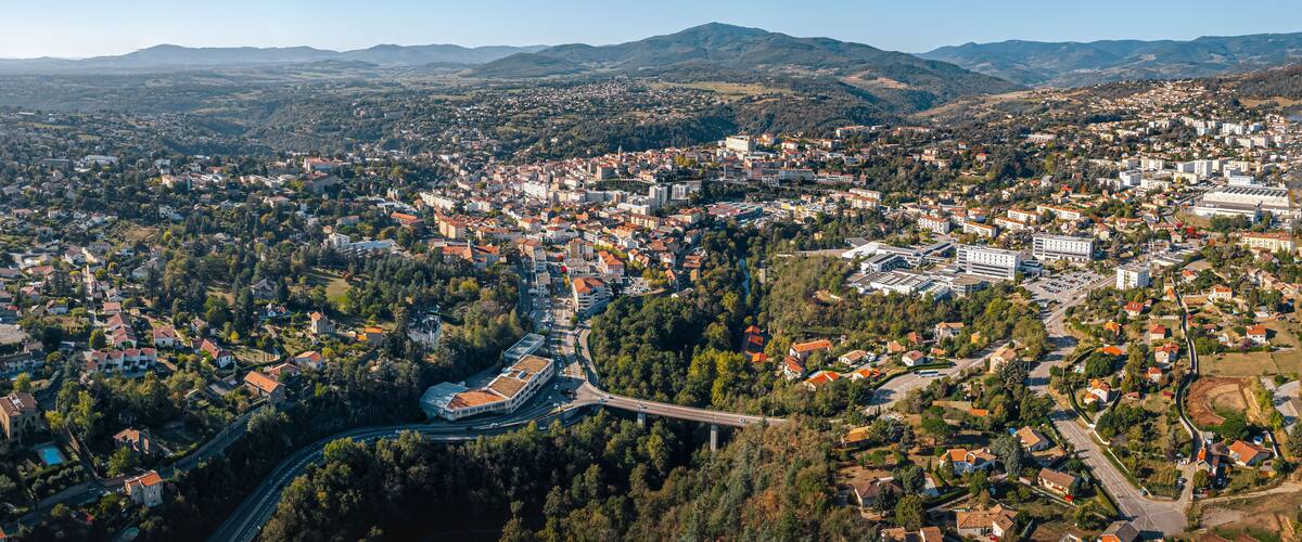 An aerial view of a town with a river, surrounded by hills and mountains.