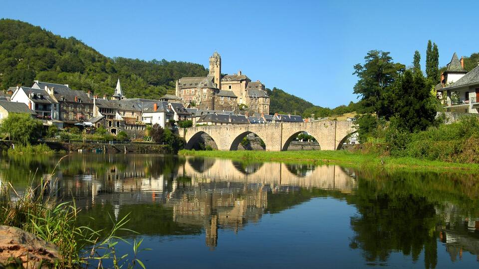 A historic town with a river, a bridge, and a castle on a hill.