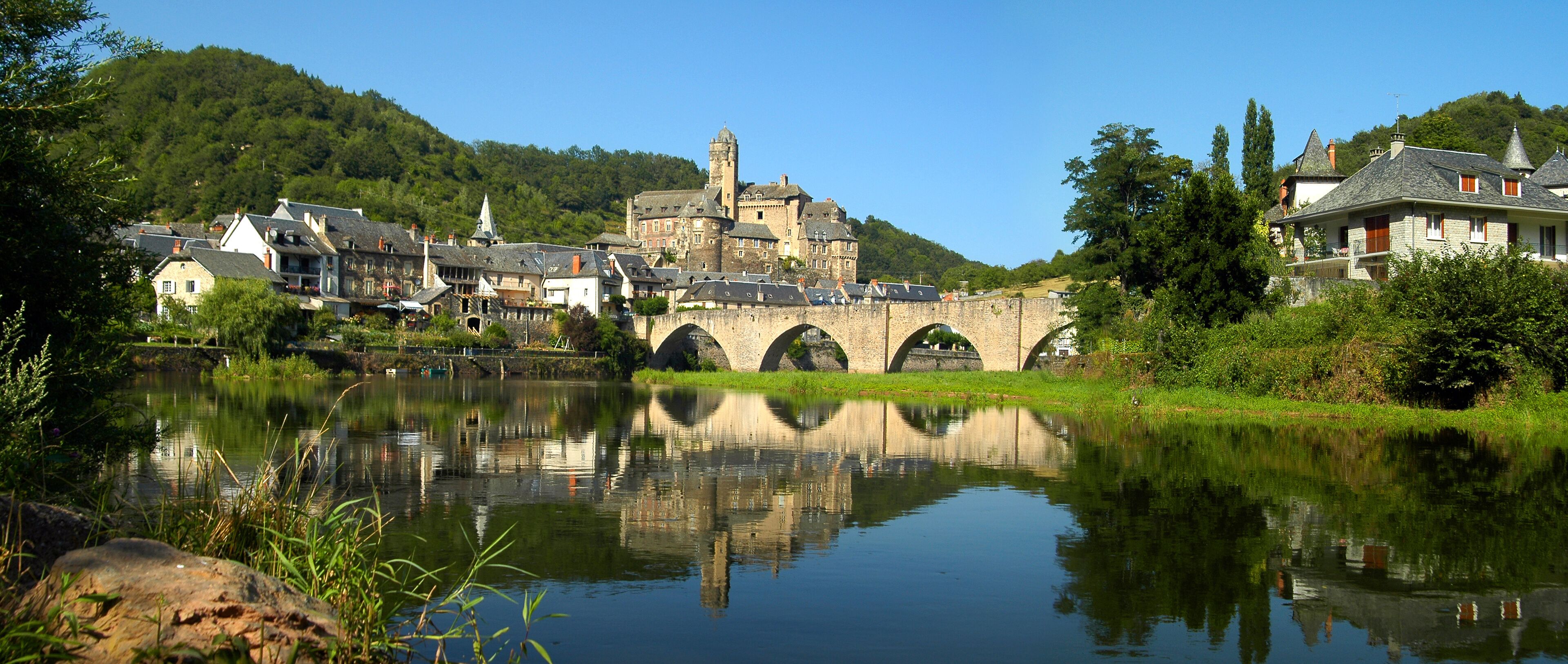 A historic town with a river, a bridge, and a castle on a hill.