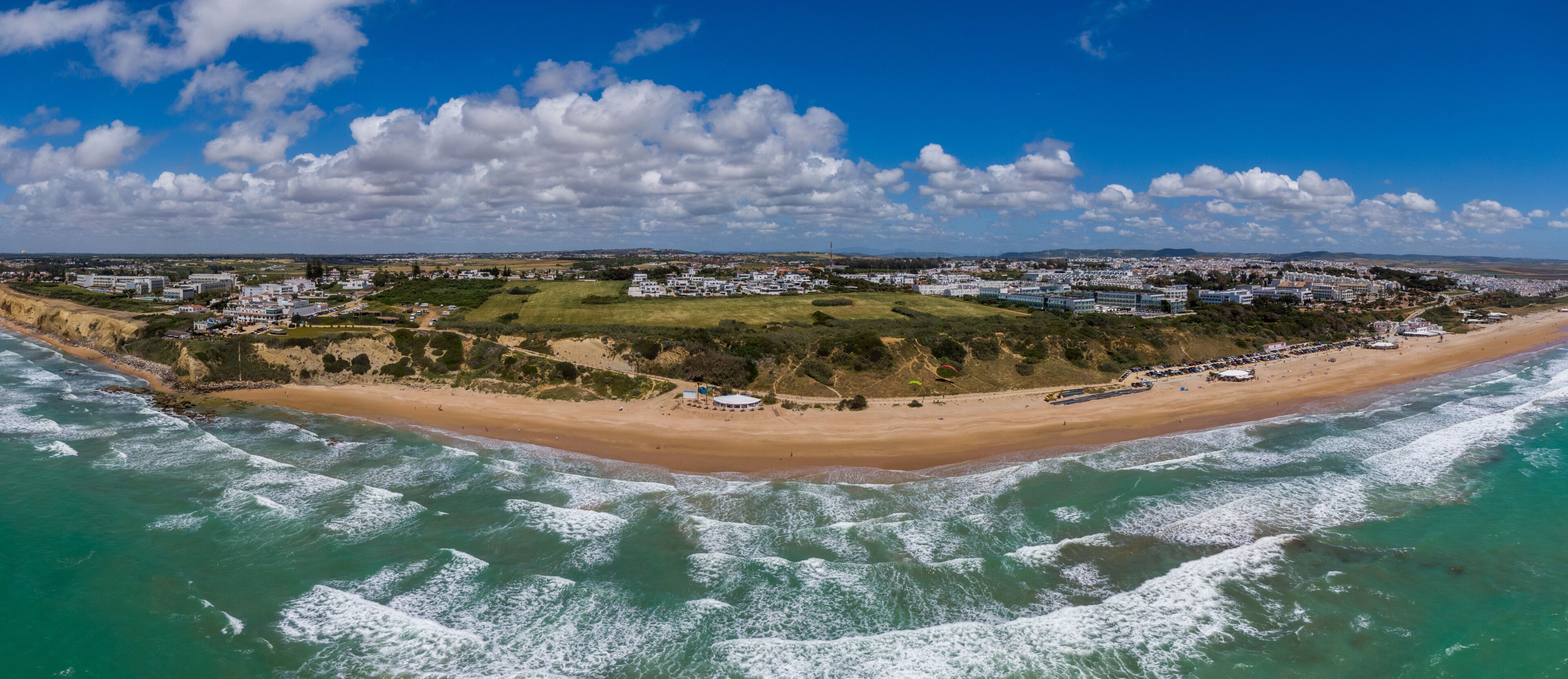 A coastal town with a beach, waves, and a clear sky.