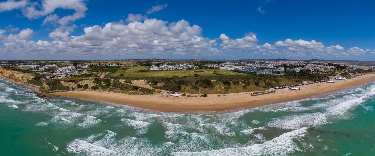 A coastal town with a beach, waves, and a clear sky.